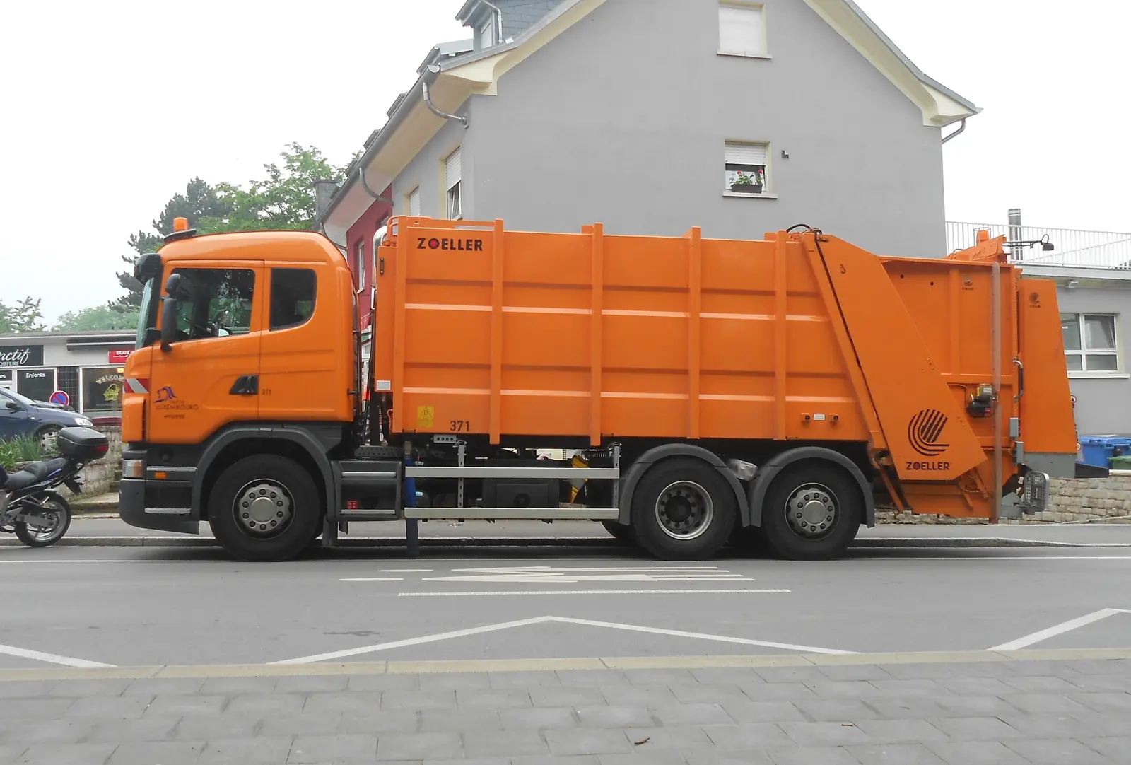 A waste collection truck servicing bins on a city street