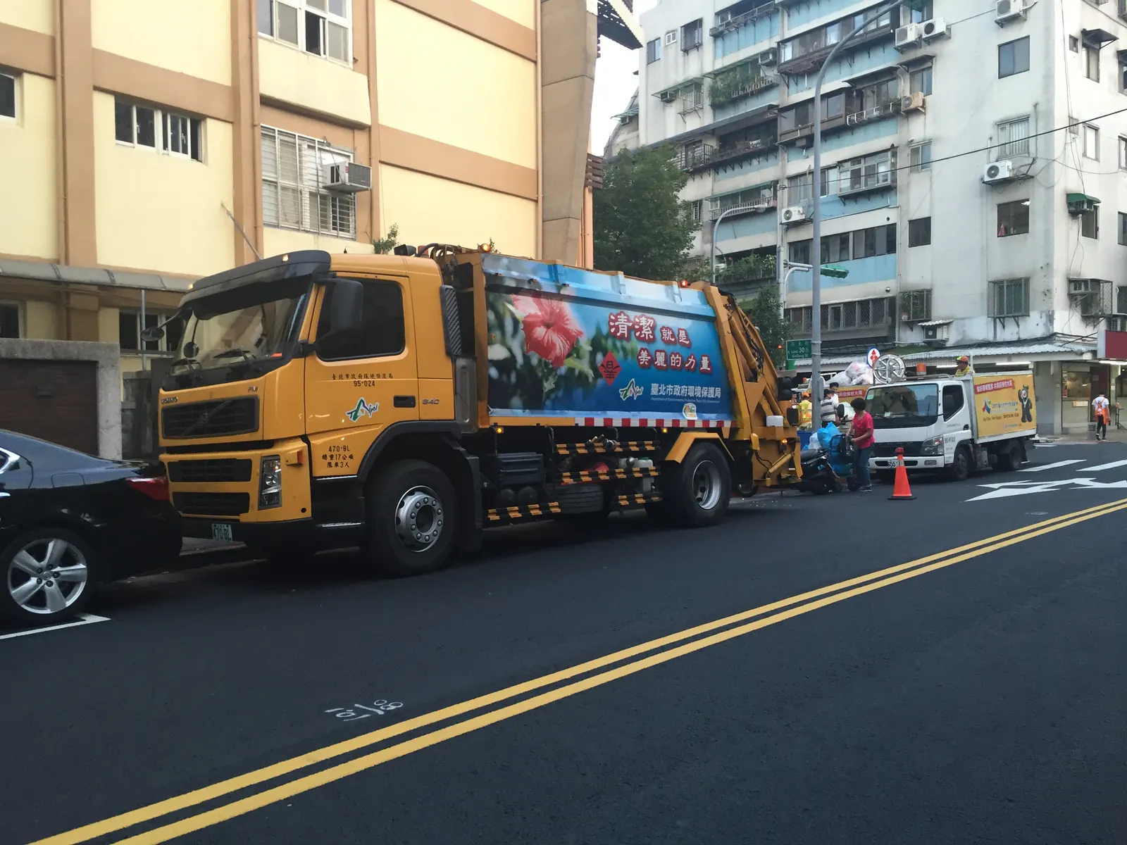 Waste collection trucks collecting garbage along an urban street
